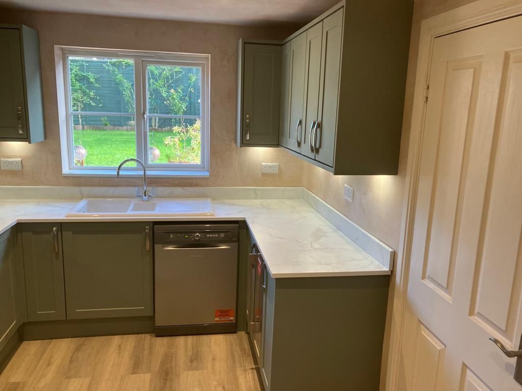 A kitchen with a sink , dishwasher , and window.