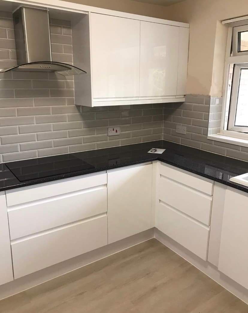 A kitchen with white cabinets and black counter tops.