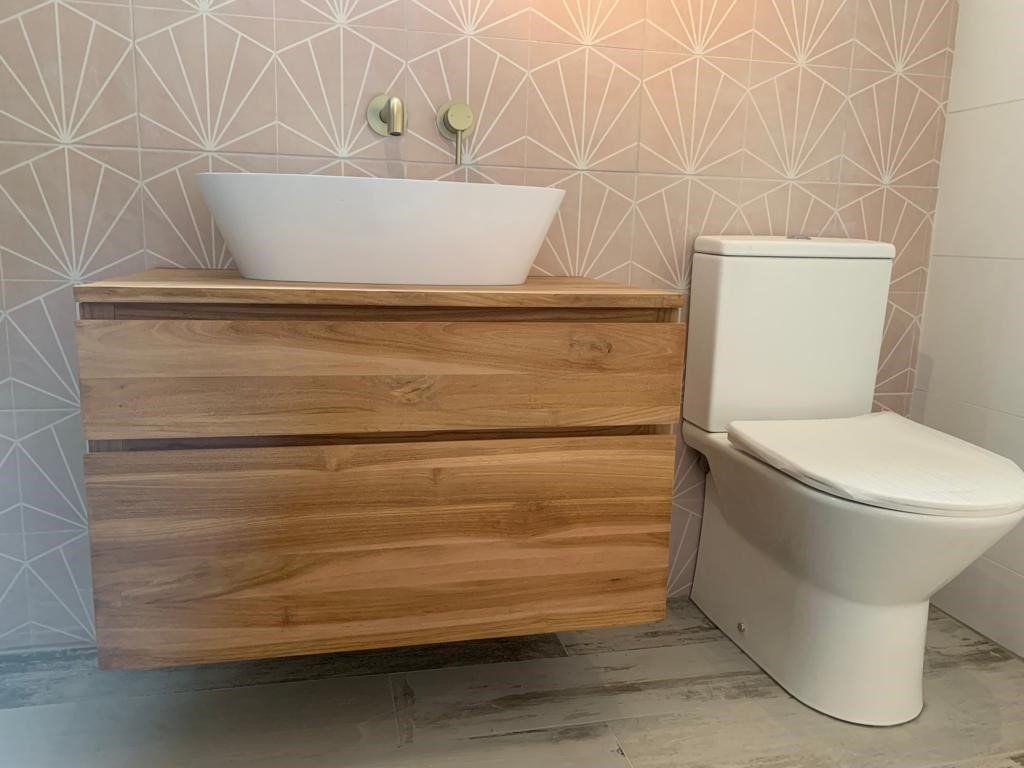 A bathroom with a wooden vanity , toilet and sink.