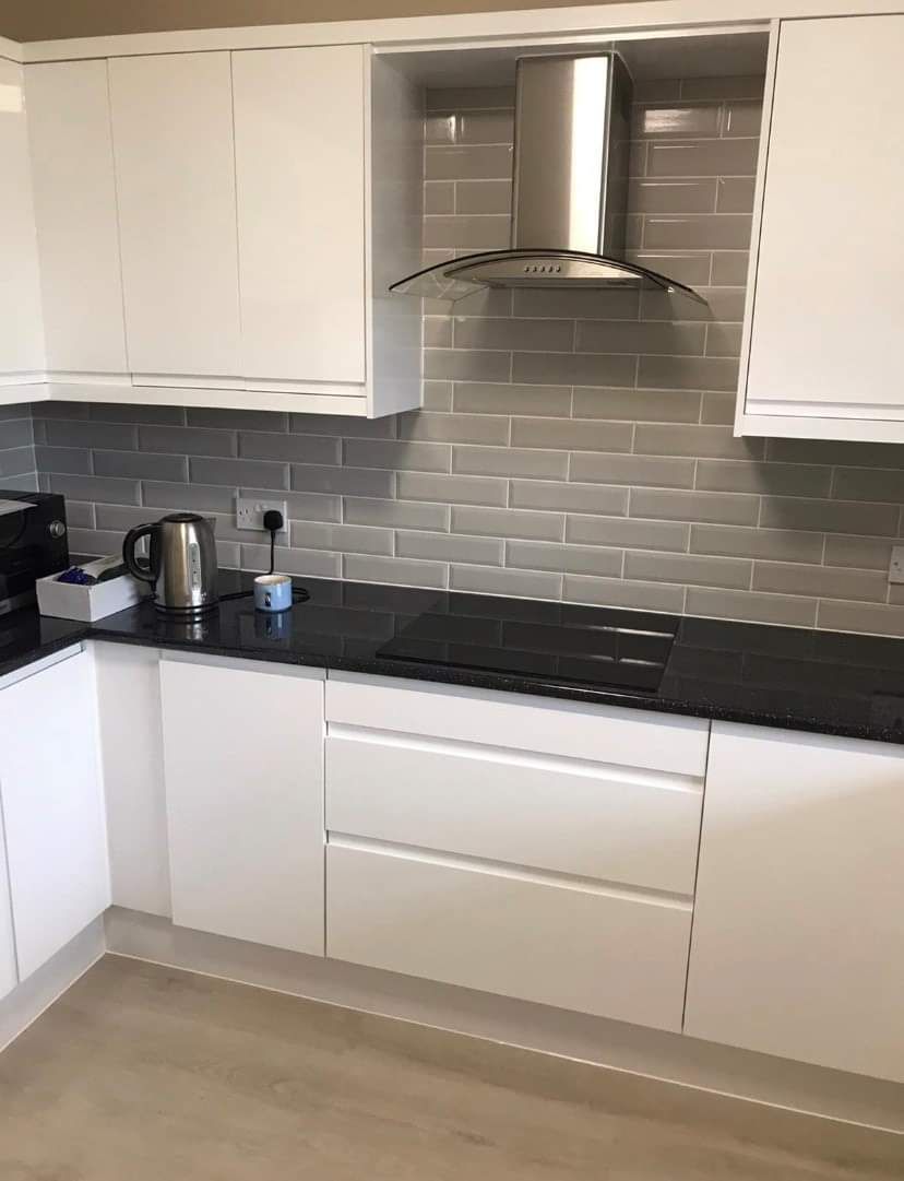 A kitchen with white cabinets and black counter tops