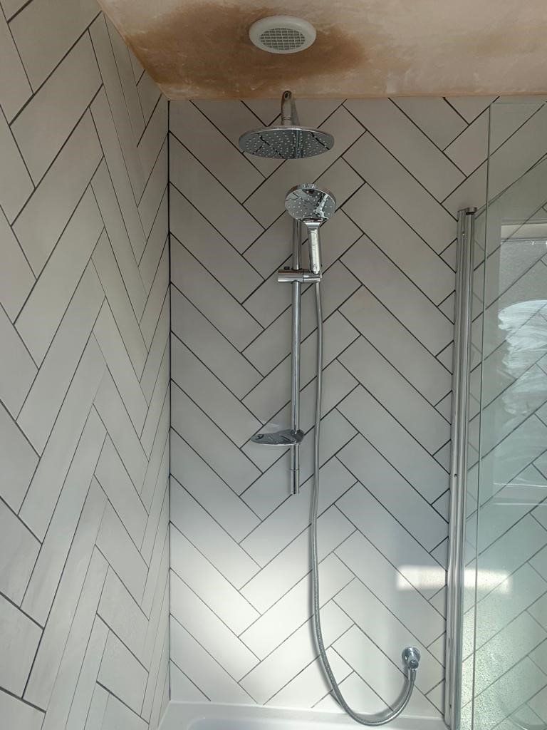 A shower head is hanging from the ceiling in a bathroom