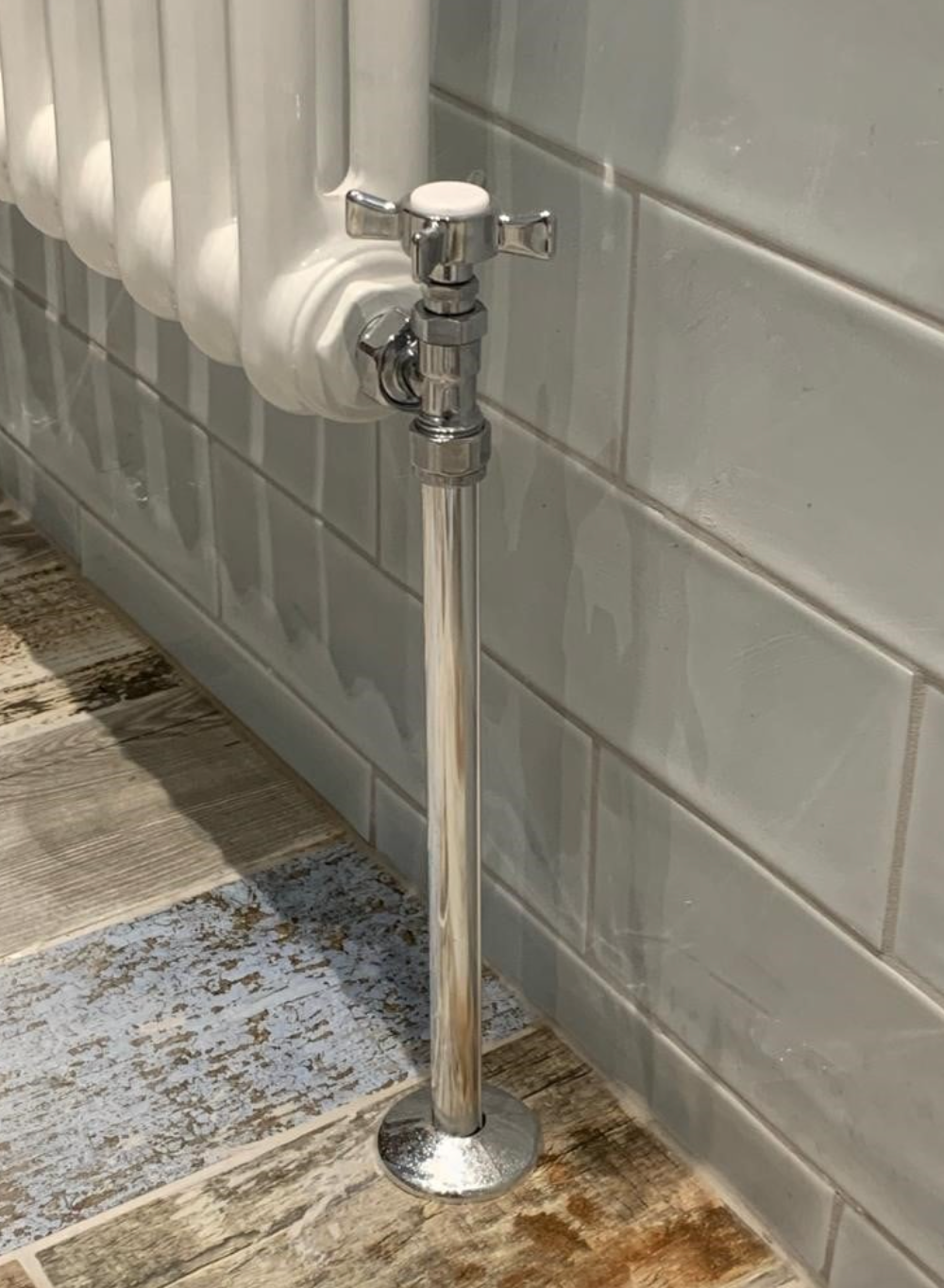A radiator is sitting on a tiled floor next to a wall.