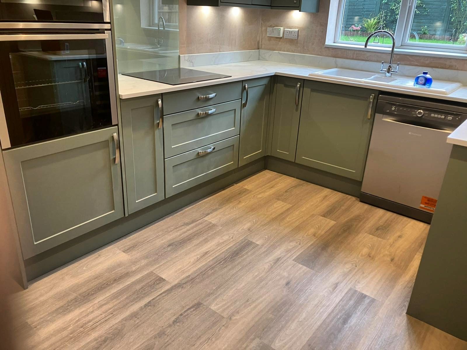 A kitchen with white cabinets and a marble counter top.