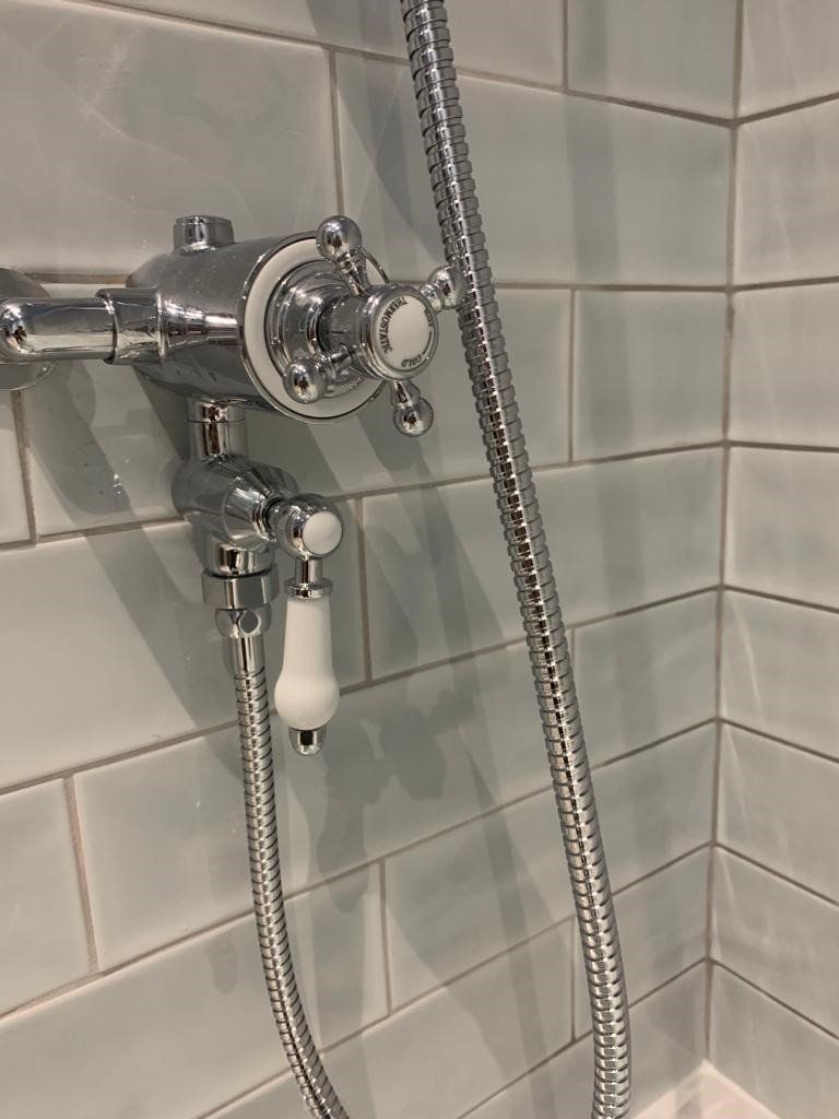 A close up of a shower head with a hose attached to it.