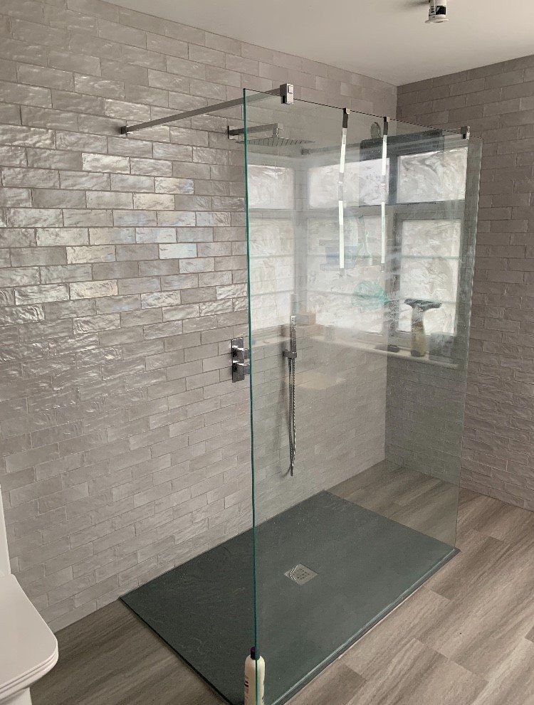 A walk in shower with a glass door in a bathroom.