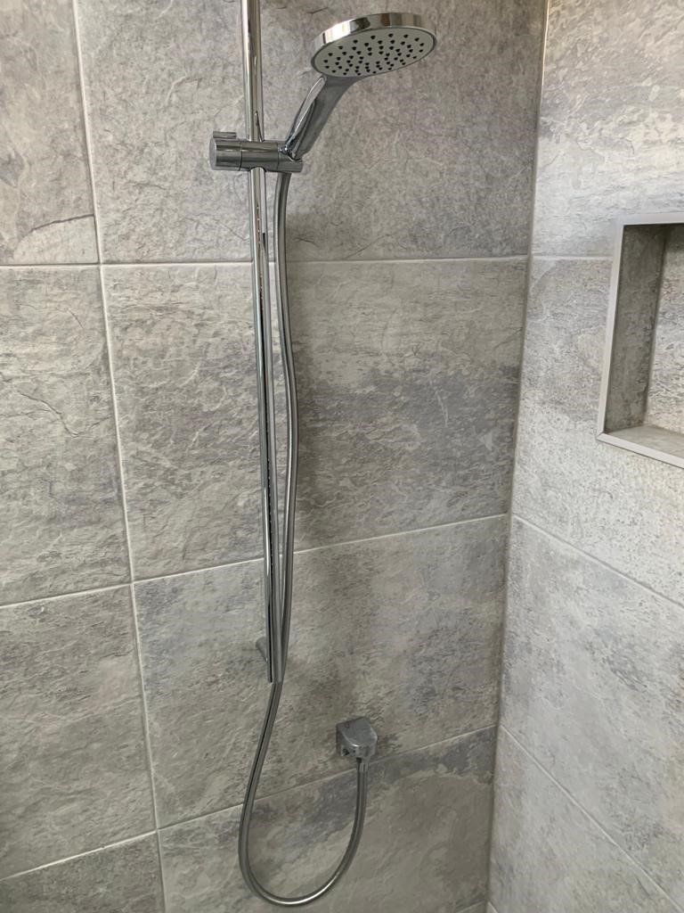 A close up of a shower head in a bathroom.