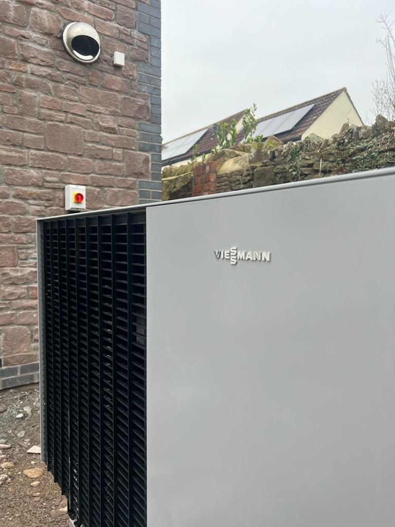 A large air conditioner is sitting on the side of a brick building.