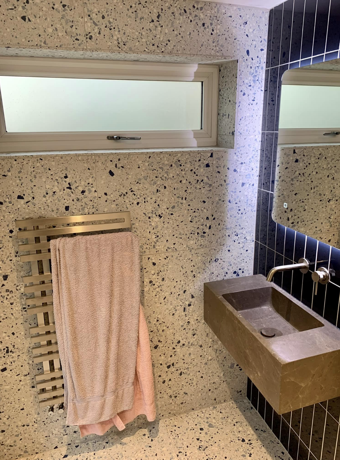 A bathroom with a sink , mirror and towel rack.