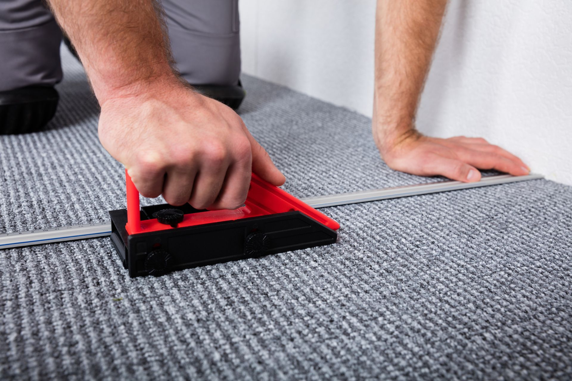 Close-up of craftsman's hands laying carpet on the floor.