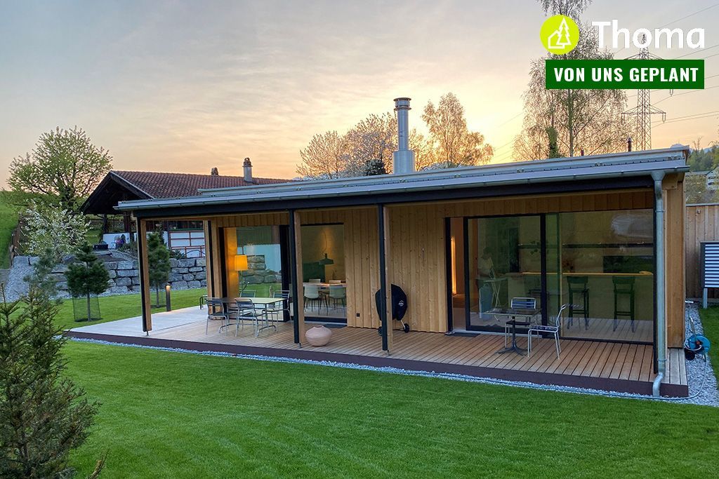 Das Ferienhaus Mariagrün mit überdachter Veranda und großer Rasenfläche davor.