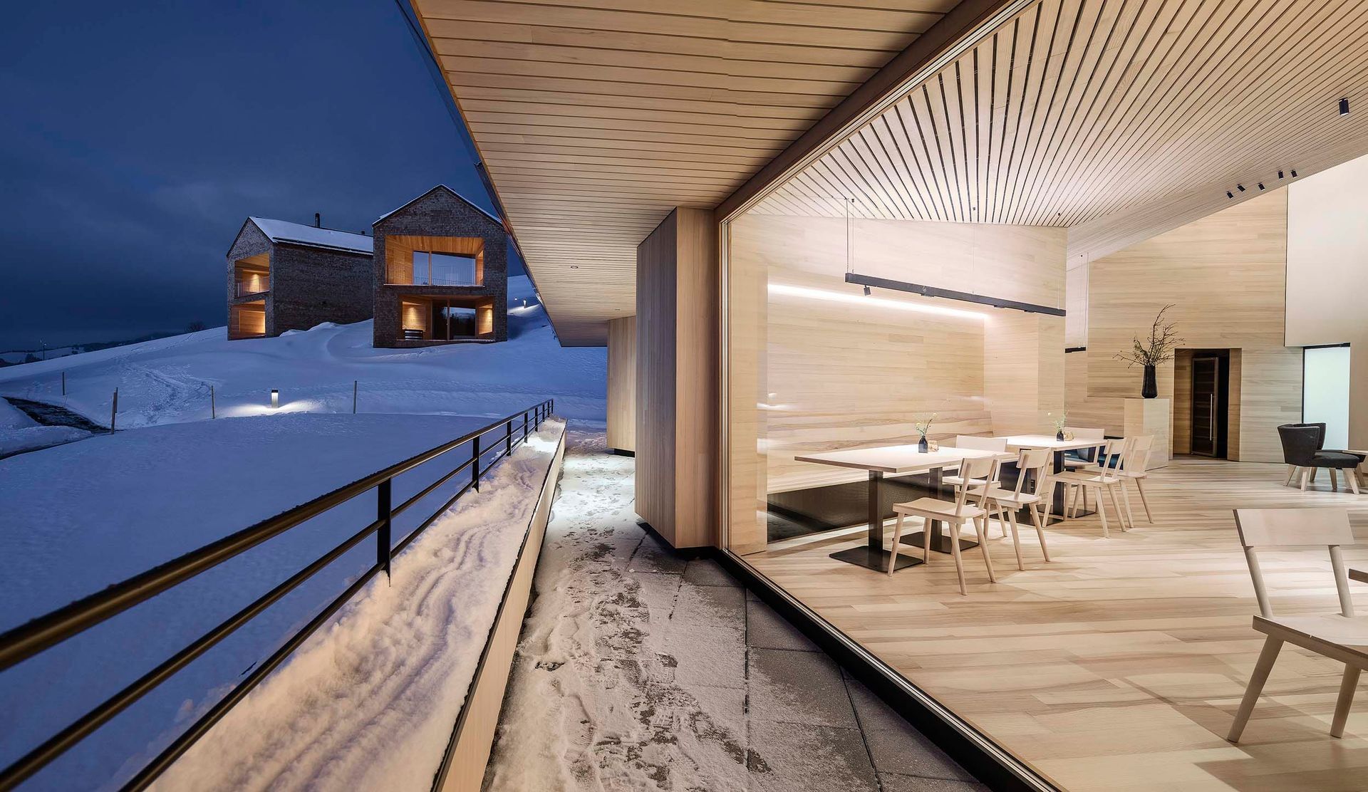 Ein Raum mit Tischen und Stühlen und einem Balkon mit Blick auf ein schneebedecktes Feld.