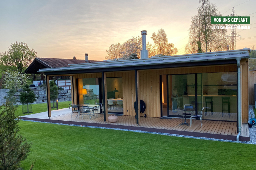 Das Ferienhaus Mariagrün mit überdachter Veranda und großer Rasenfläche davor.