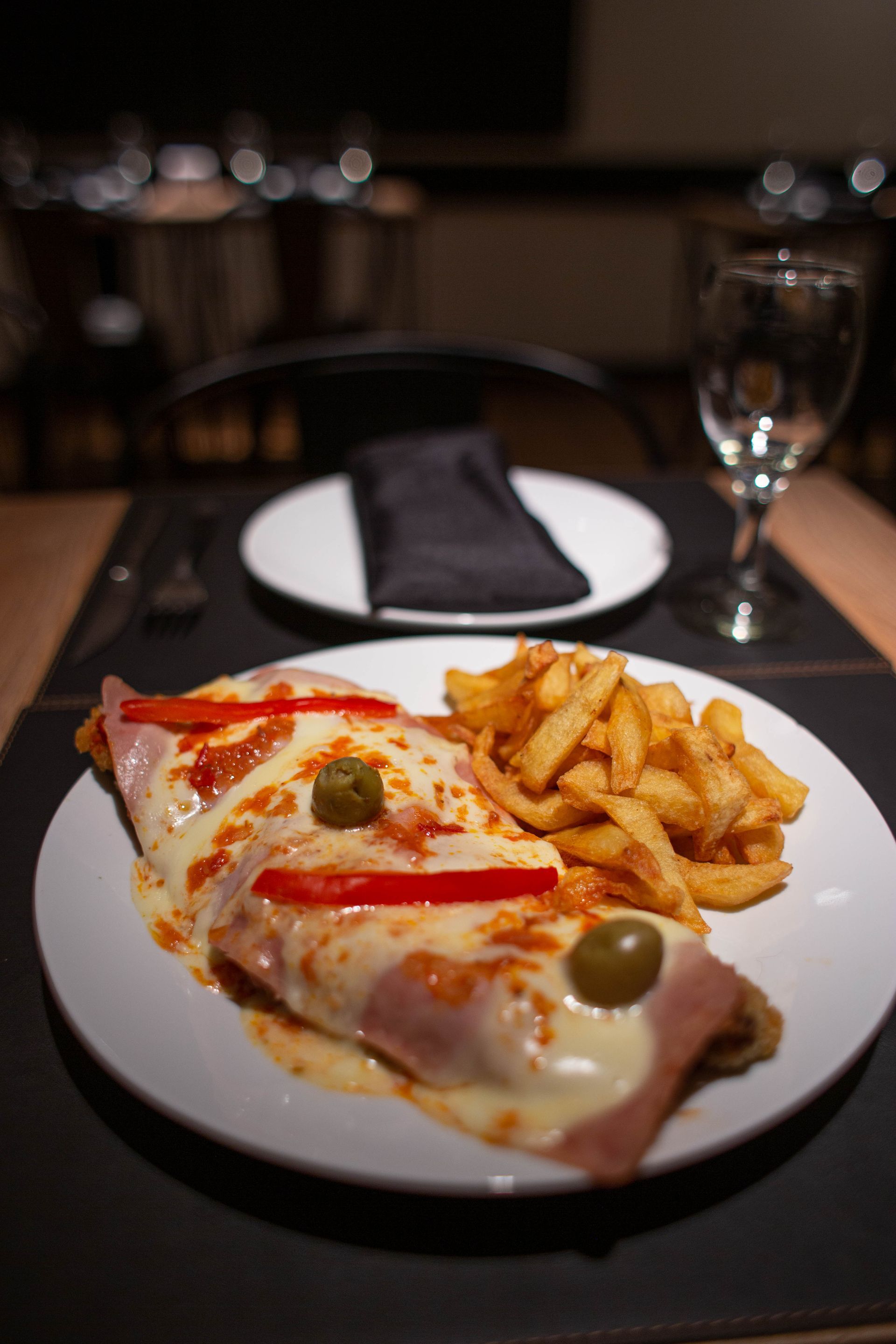 Un plato de comida con patatas fritas y una copa de vino sobre una mesa.