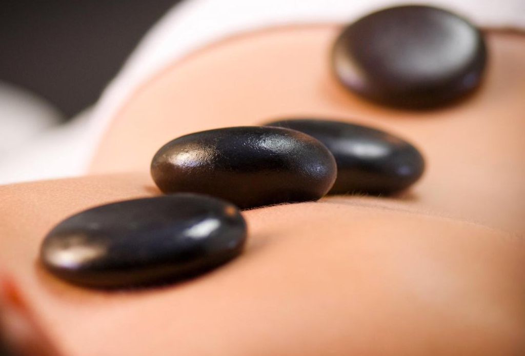 Una persona recibe un masaje con piedras calientes en la espalda.