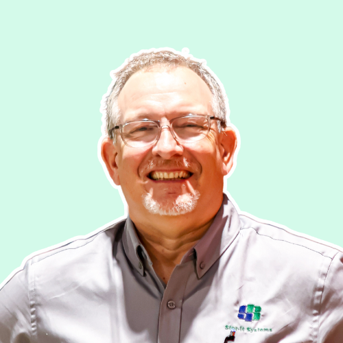 A man with glasses and a beard is smiling for the camera