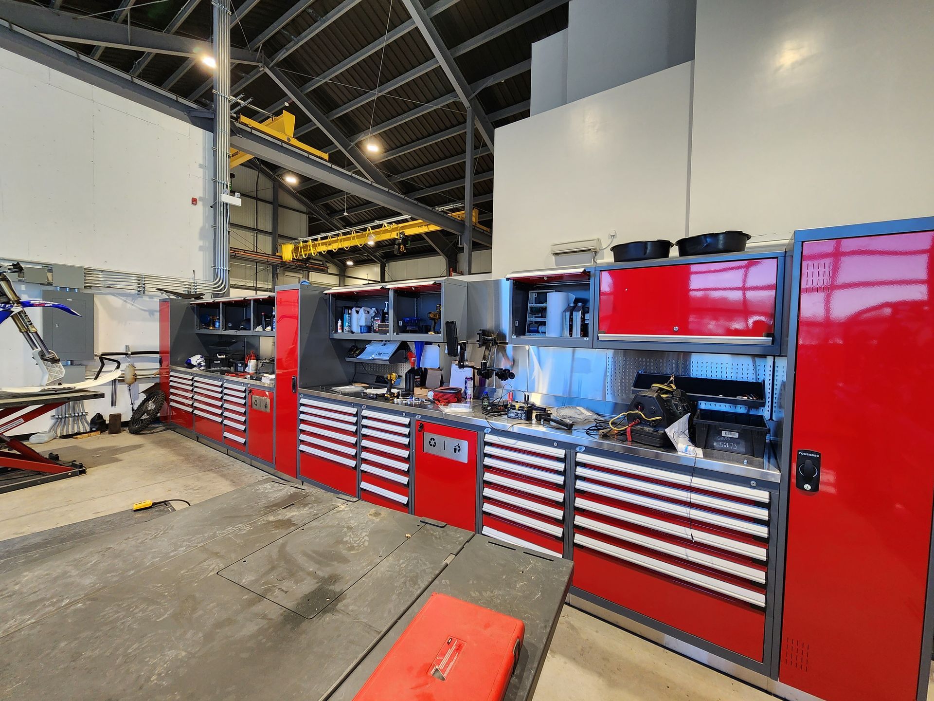 A garage with a lot of red cabinets and drawers.