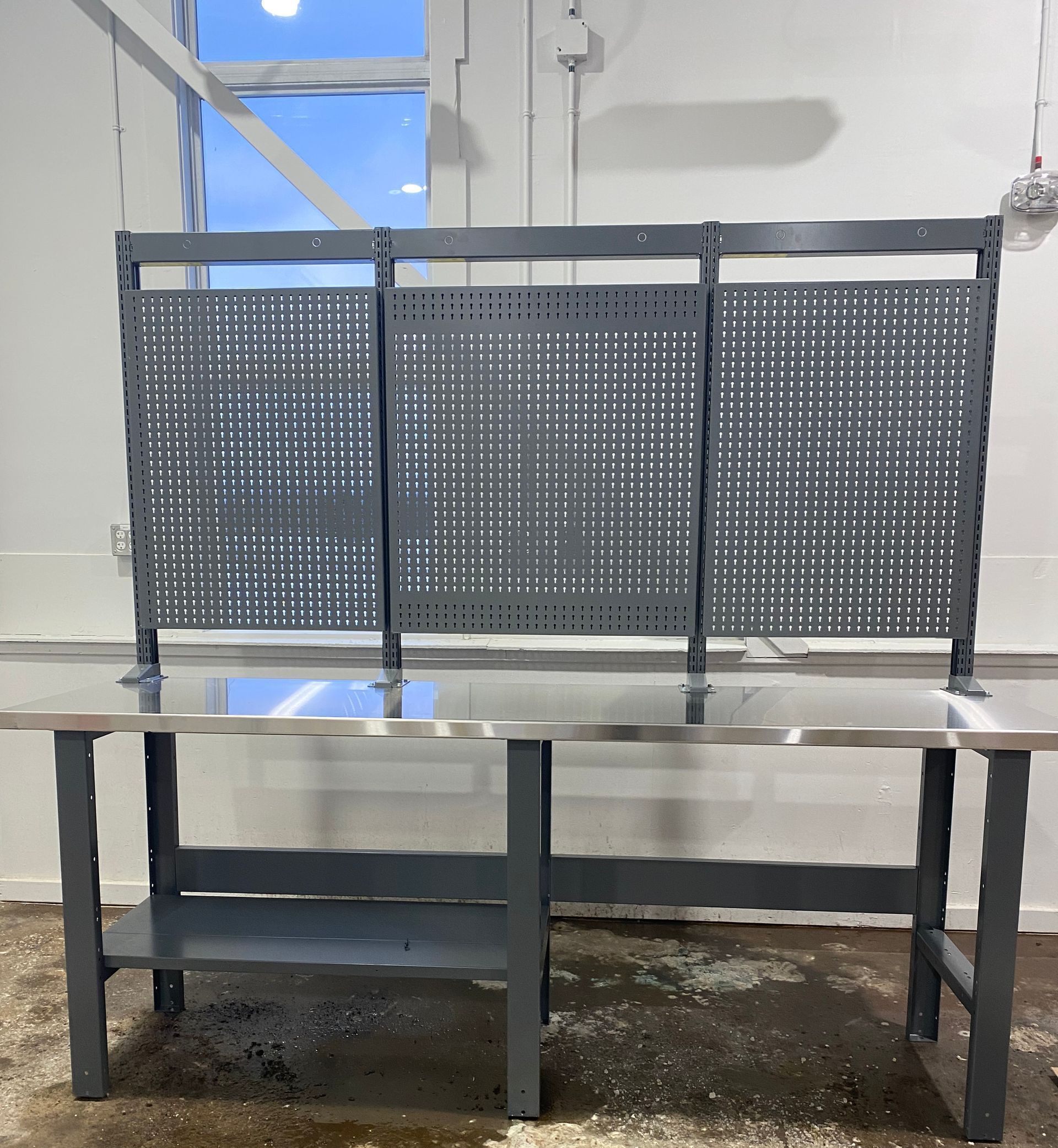 A metal bench with a perforated back sits in front of a window