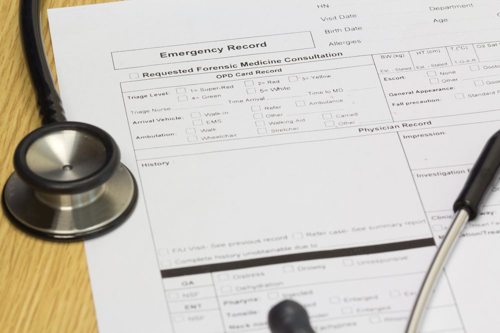 A stethoscope resting on a medical emergency record form on a wooden surface.