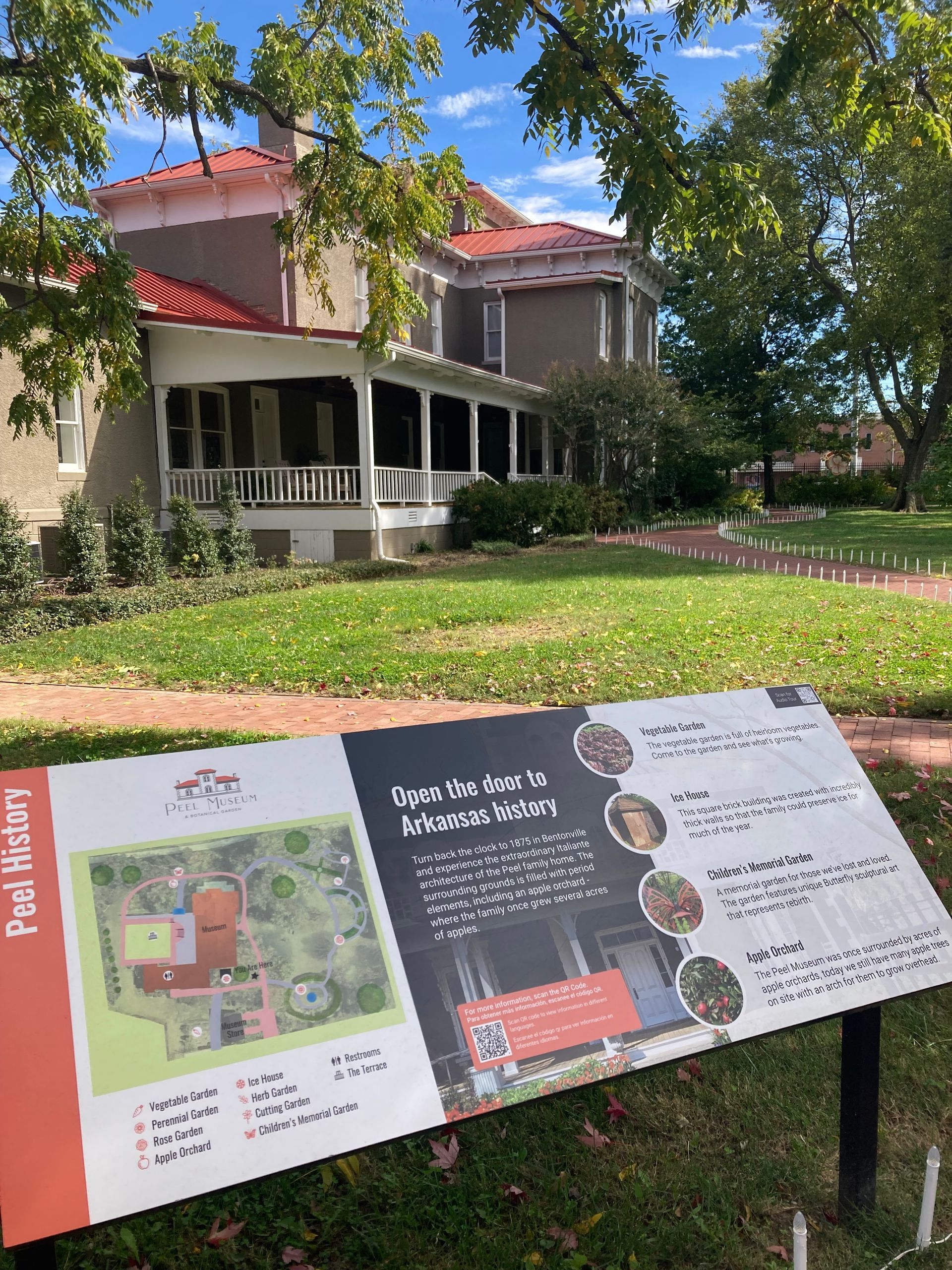 A sign is sitting in front of a large house.
