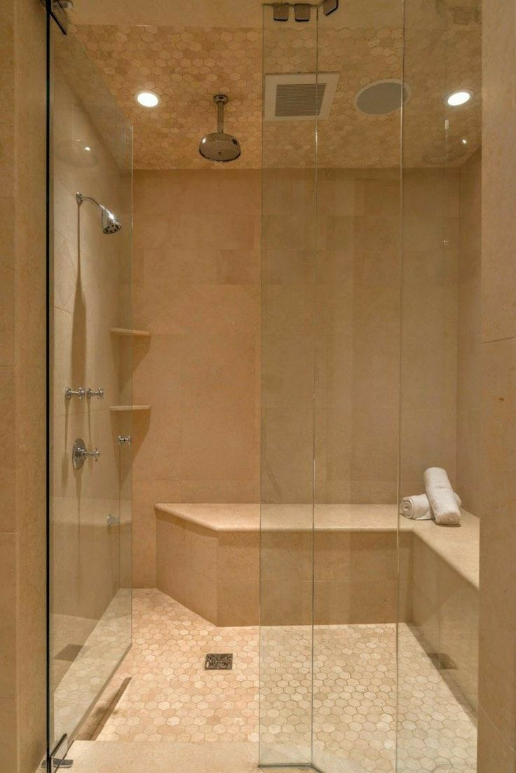 Un baño con ducha a ras de suelo y un banco.