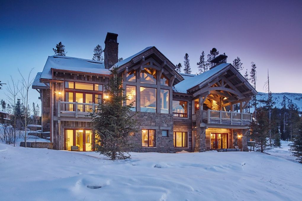 Snow-covered log cabin glowing with warm lights at dusk in a winter forest