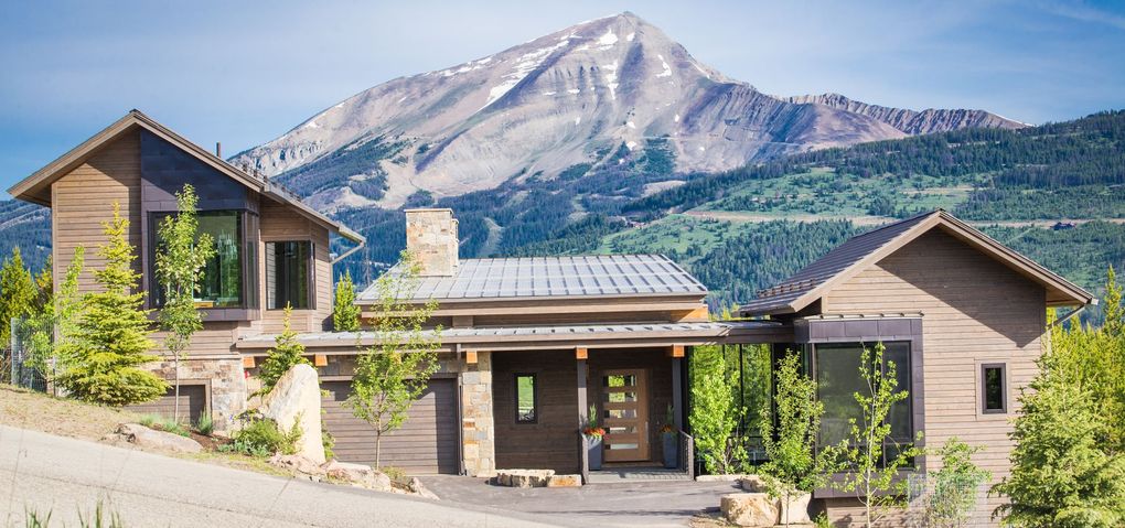 Mountain lodge with solar panels in front of a rocky peak under a clear sky