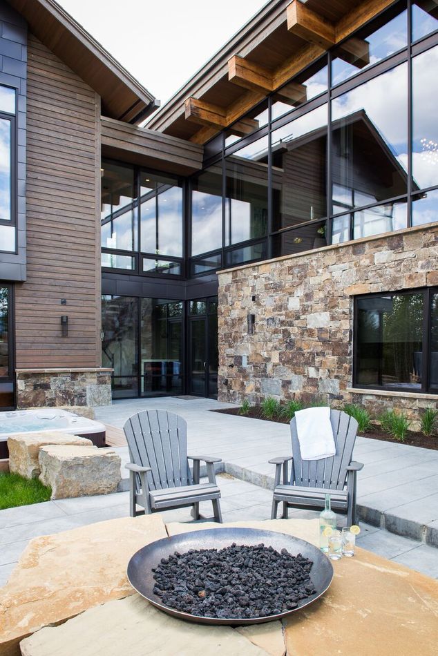 Modern courtyard with stone fire pit, two Adirondack chairs, and glass-walled building exterior