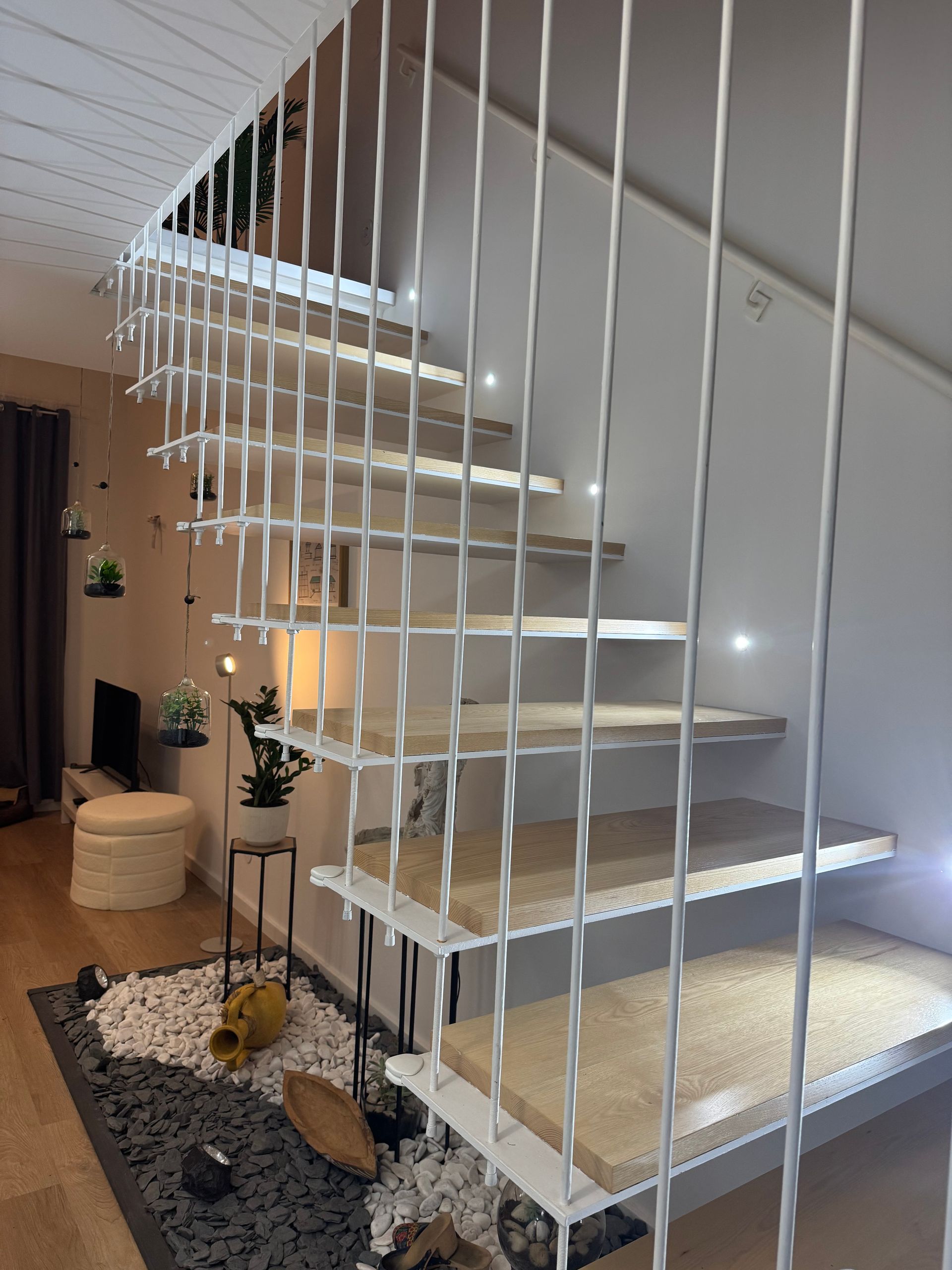 Escada moderna com corrimão de metal branco e degraus de madeira clara.