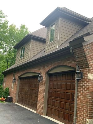 A large brick house with three garage doors and a roof.