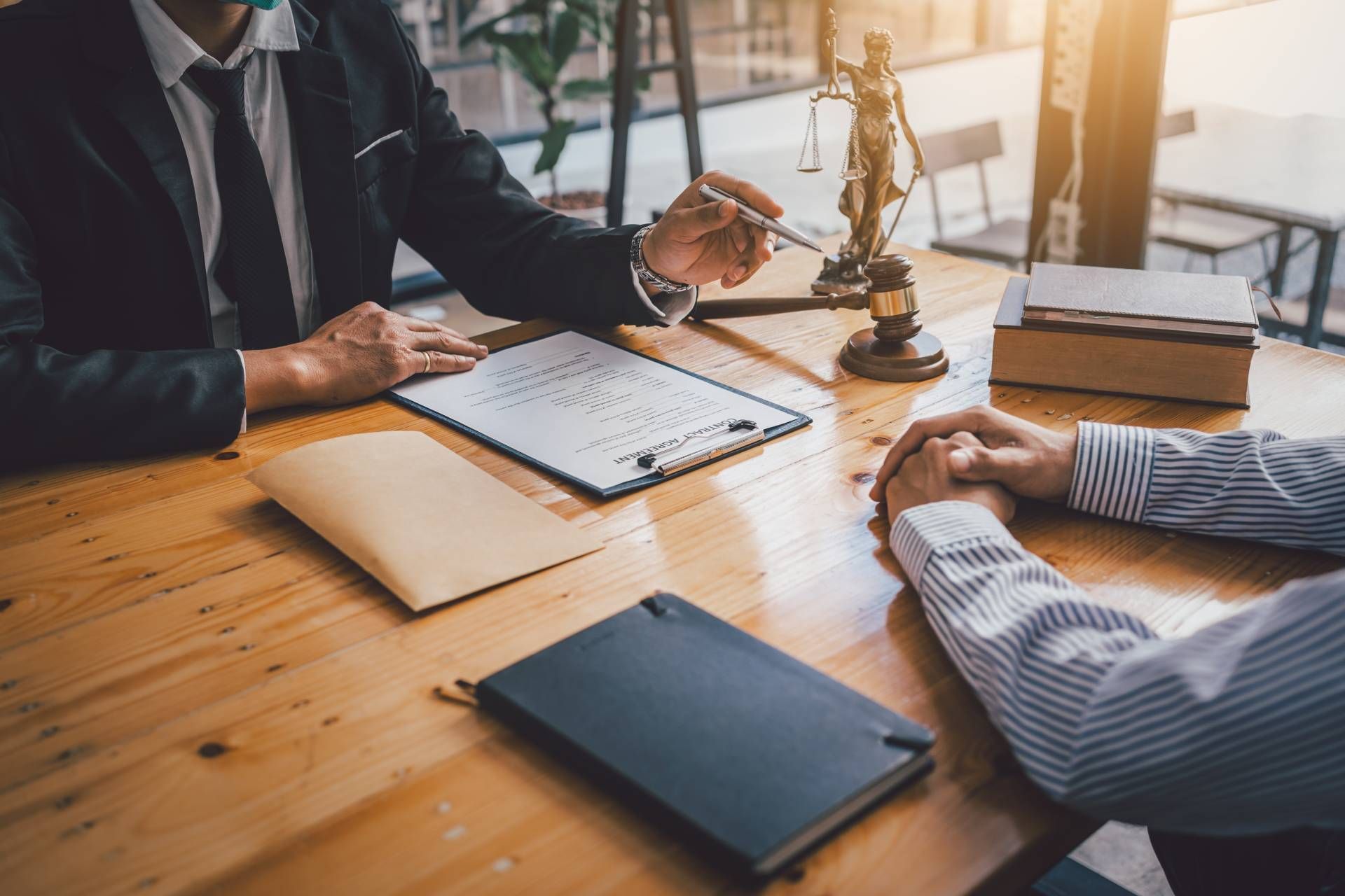 Lawyer pointing at document with client at a wooden table in office setting.