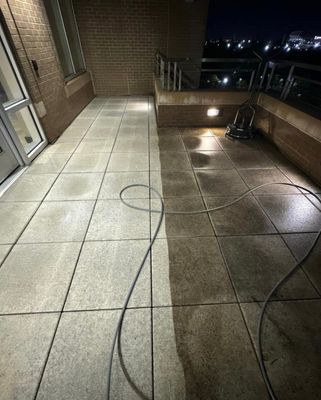 A man is using a high pressure washer to clean a pole.