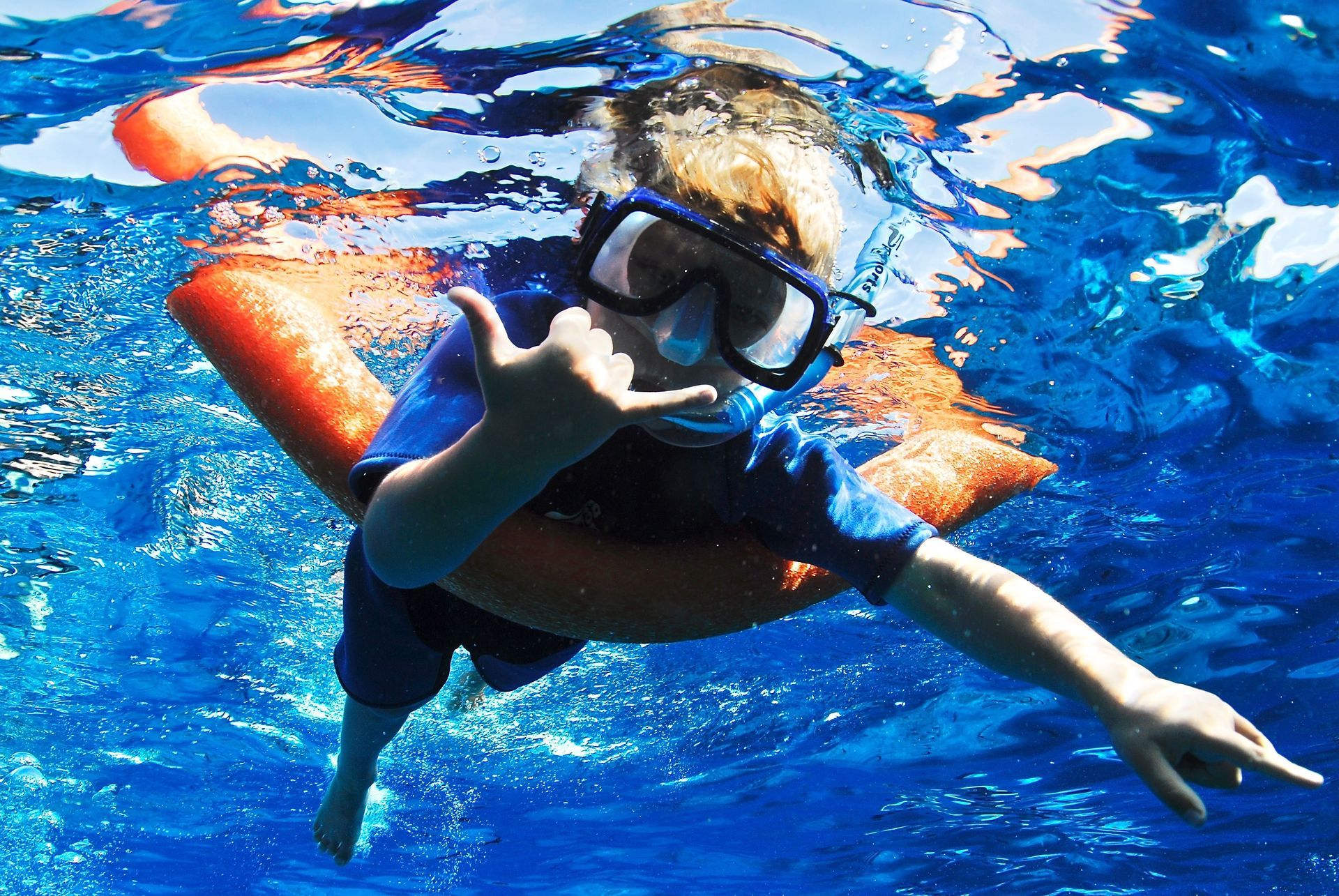 A young boy wearing a mask and goggles is swimming in the ocean