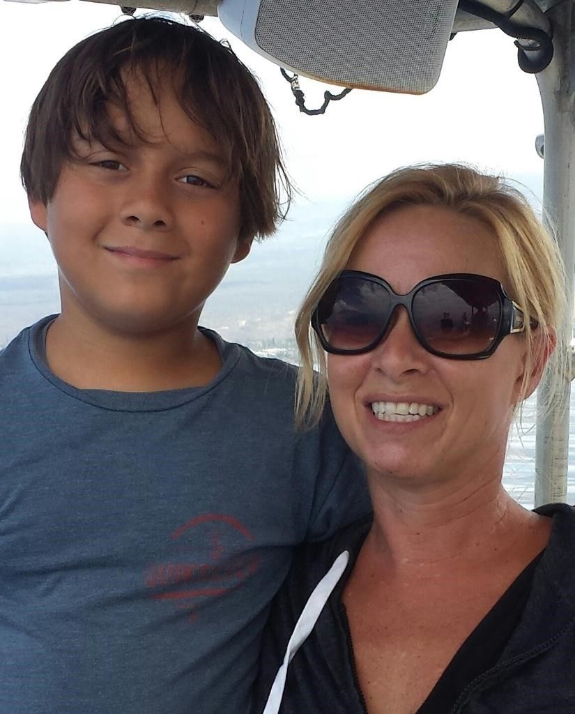 A woman and a boy wearing sunglasses are posing for a picture