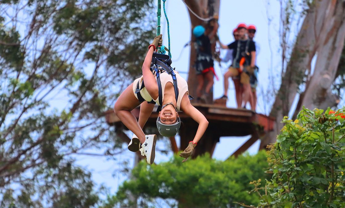A woman is flying through the air on a zip line.