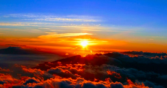 The sun is setting over the clouds in the sky.