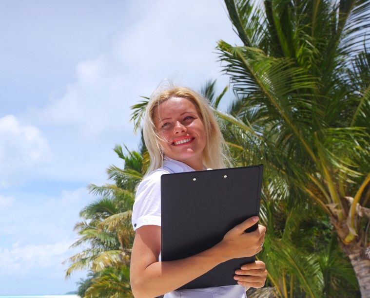 A woman holding a clipboard in front of palm trees