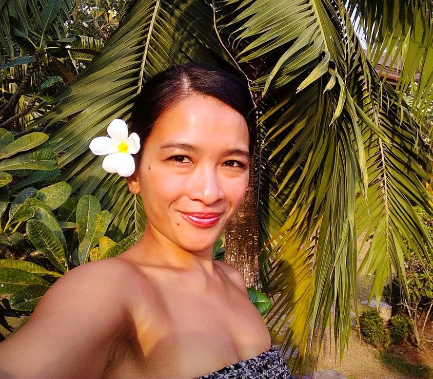 A woman taking a selfie with a flower in her hair