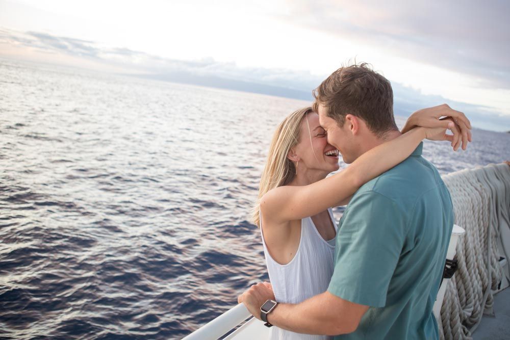 A man and a woman are hugging on a boat in the ocean.