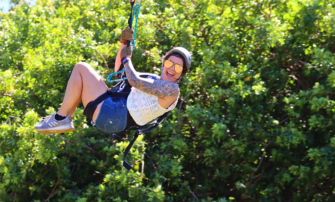 A woman is flying through the air on a zip line.