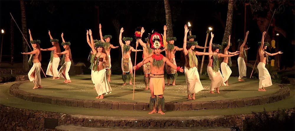 A group of people are dancing in a circle on a stage at night.