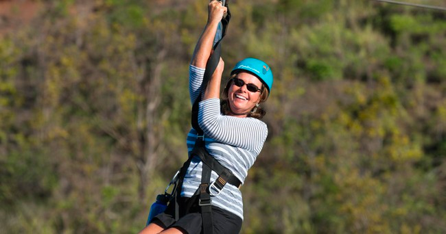 A woman is flying through the air on a zip line.