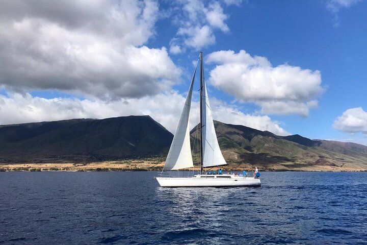 A sailboat is floating on top of a body of water with mountains in the background.