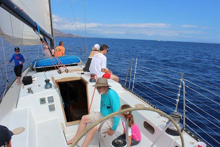 A group of people are on a sailboat in the ocean.