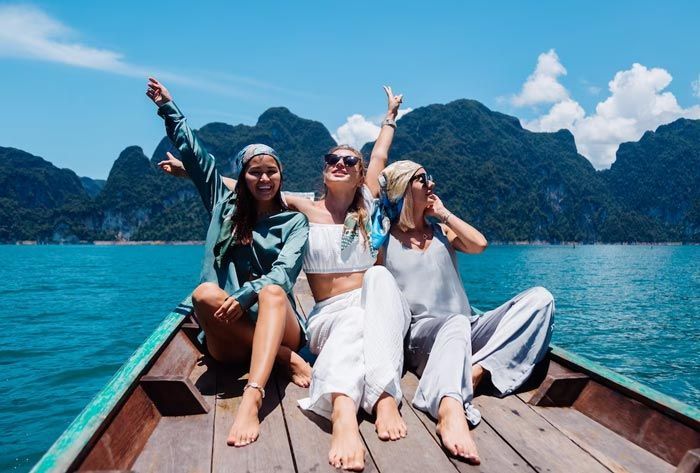Three women are sitting on the deck of a boat in the water.