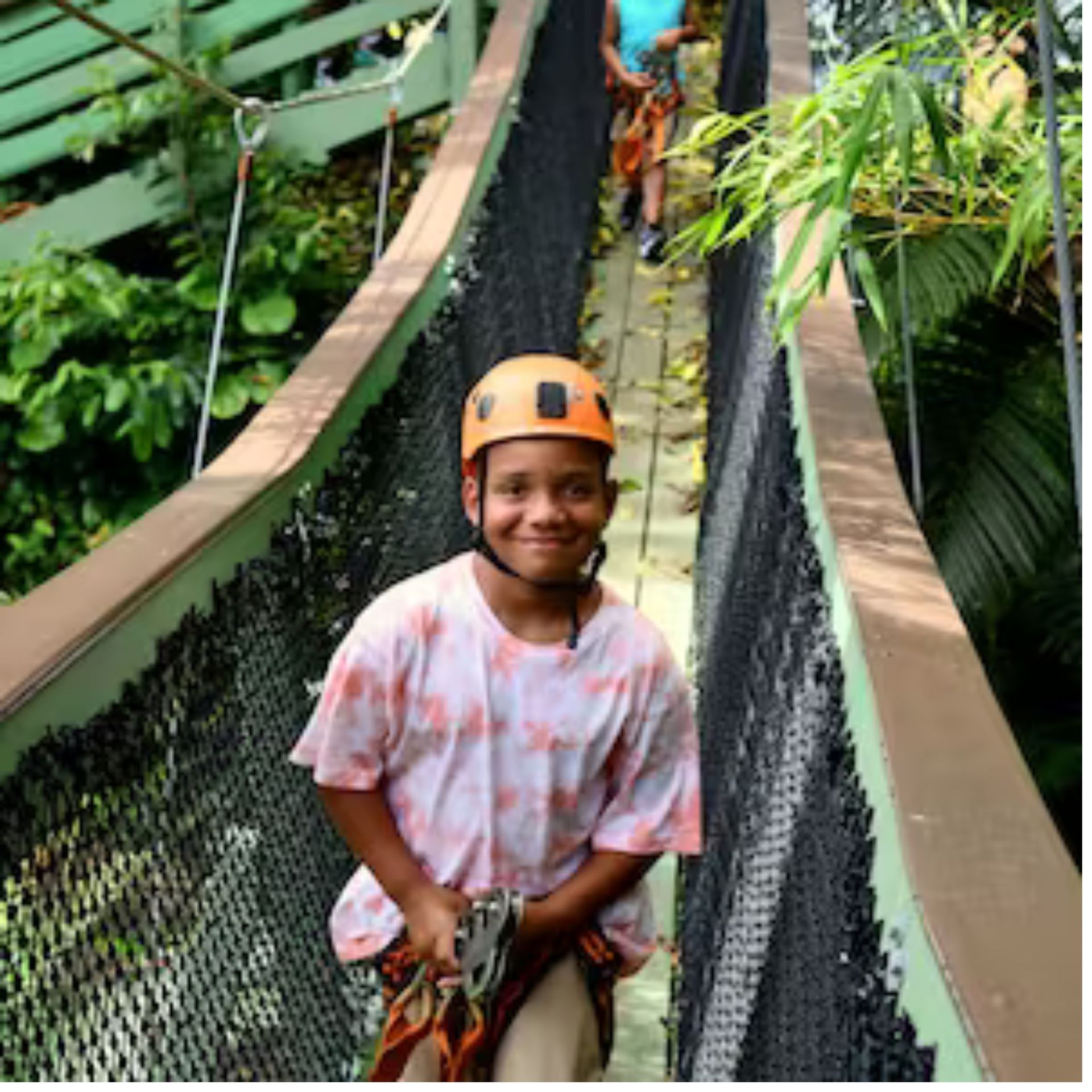 A young boy wearing a helmet is walking across a bridge