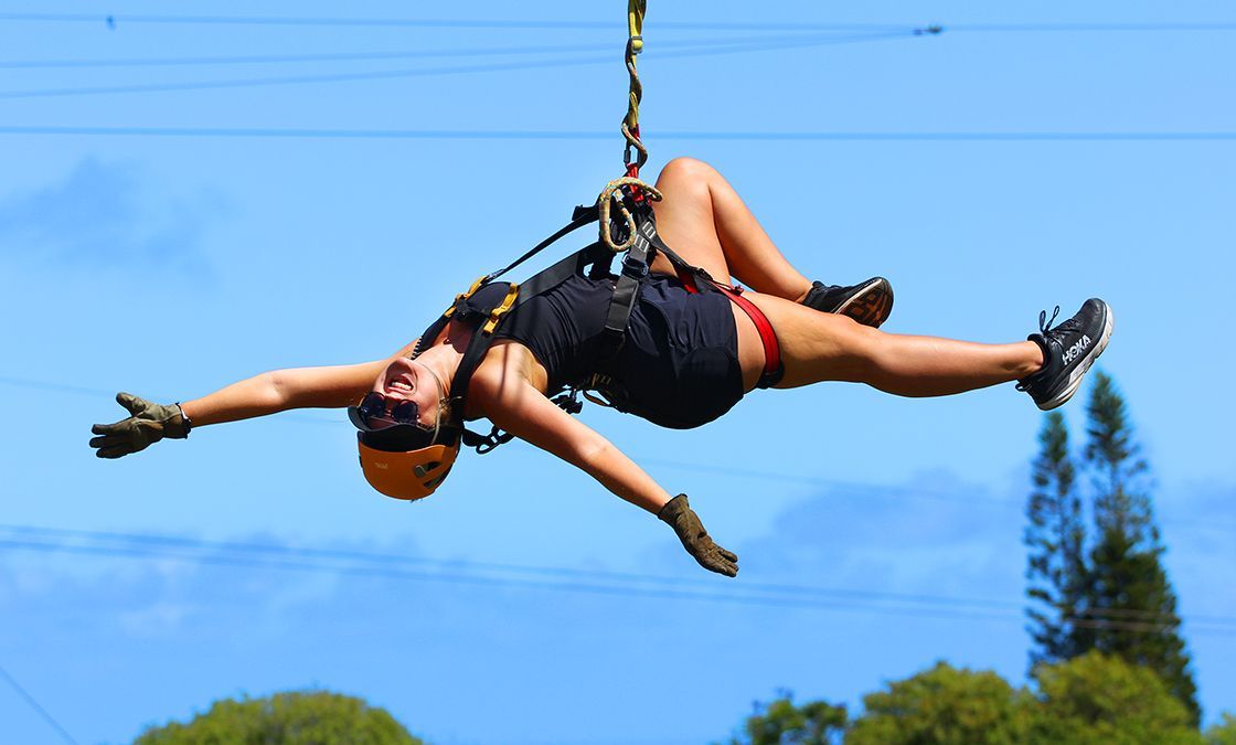 A woman is flying through the air on a zip line.