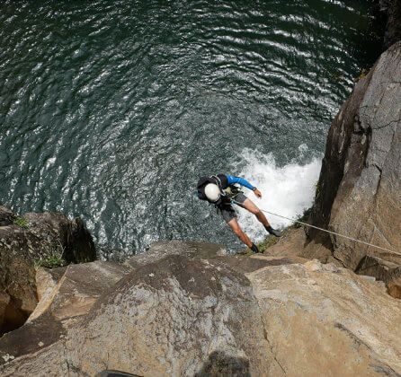 A person is climbing down a cliff into a body of water.