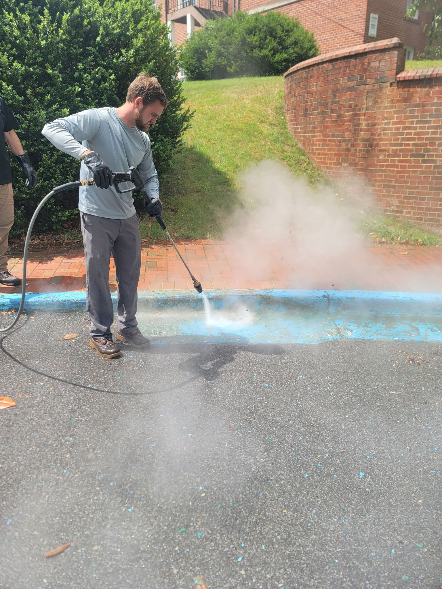A man is using a high pressure washer to clean a parking lot.