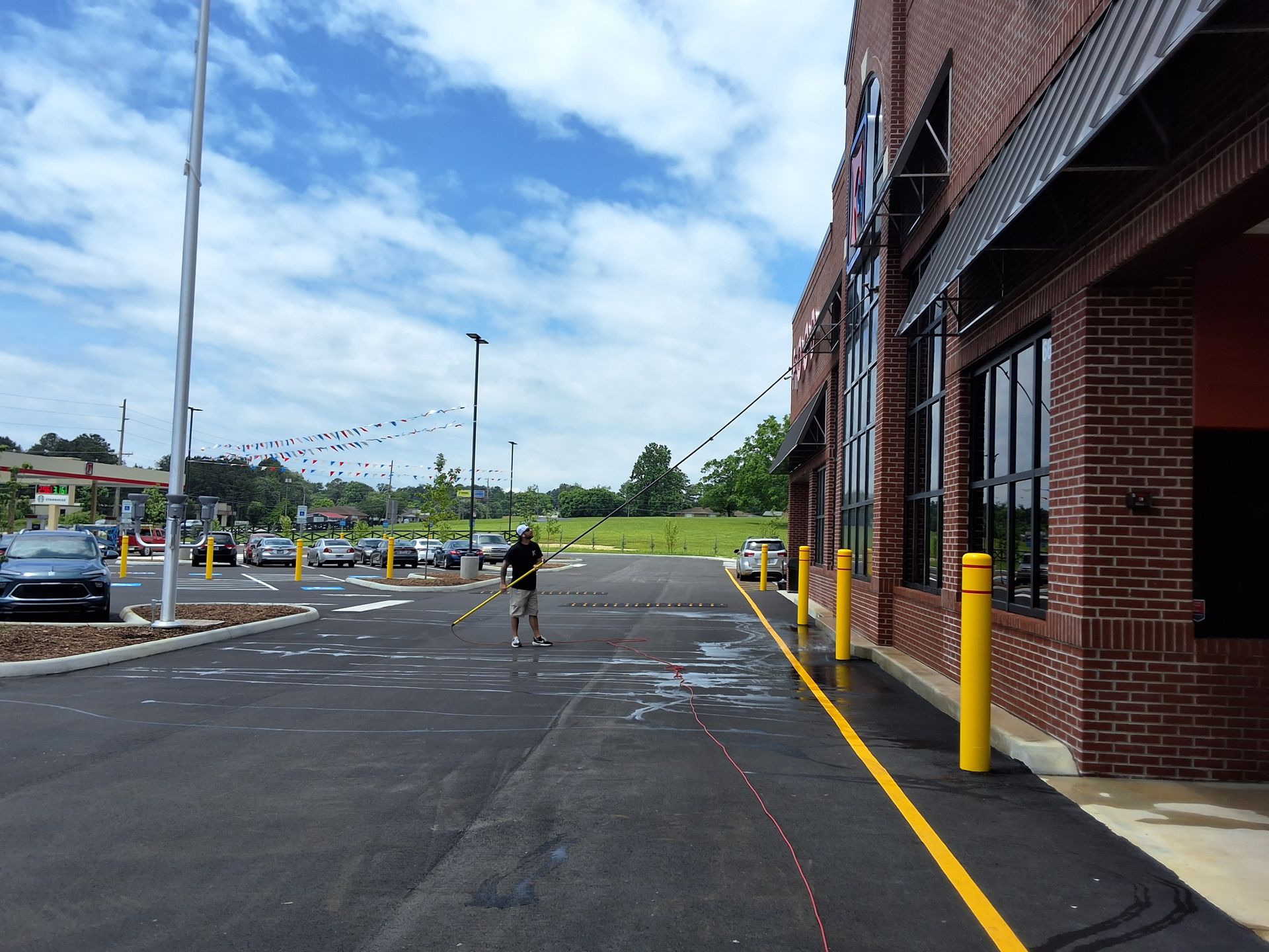 A man is standing in a parking lot next to a brick building.
