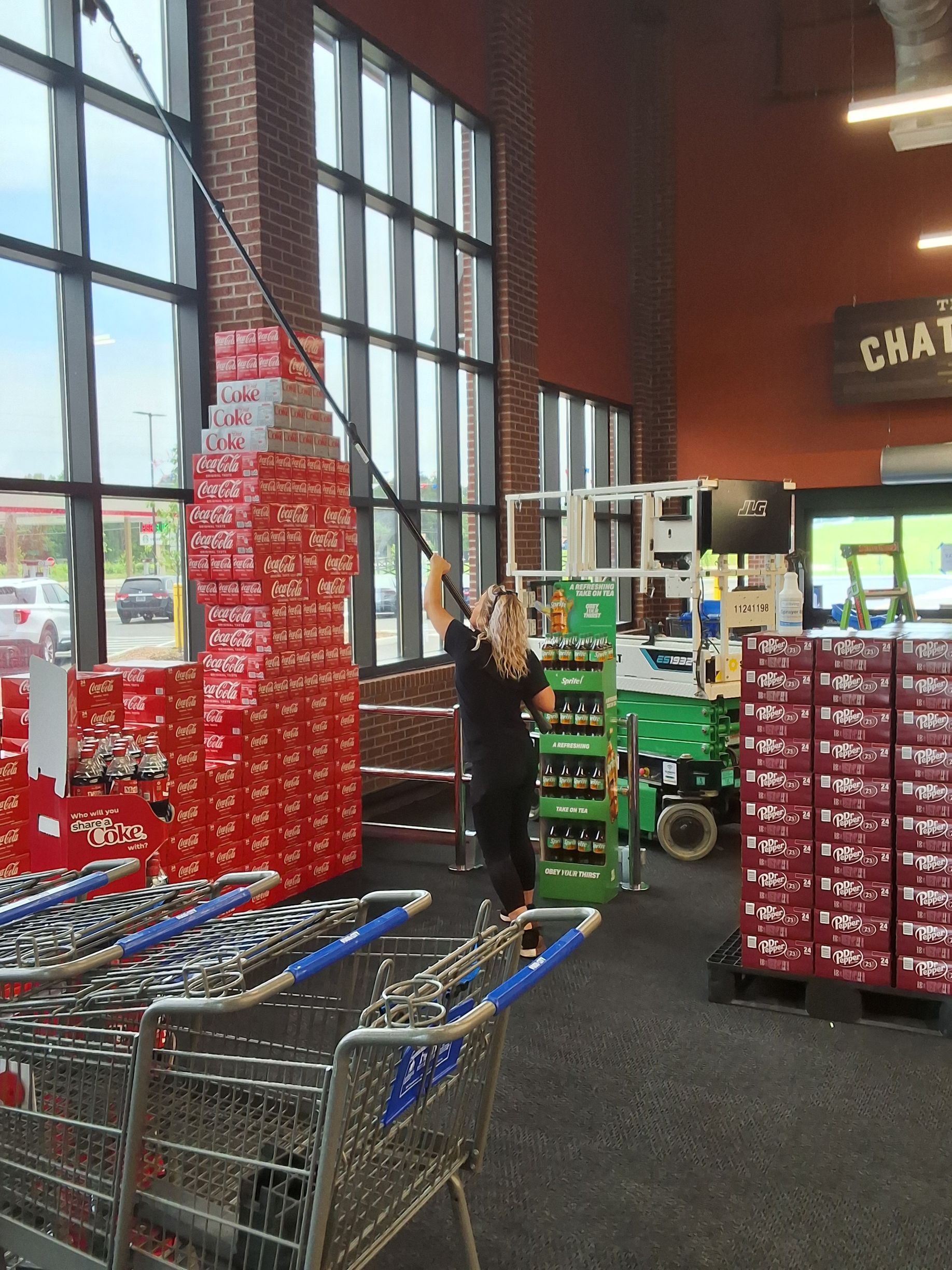 A woman is cleaning a large coca cola bottle in a store